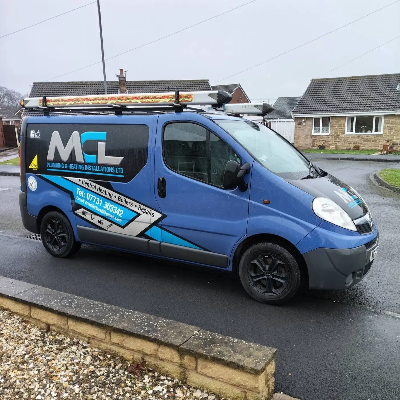 The MCL Plumbing & Heating branded van, blue with grey and black livery, parked on a residential street showing the full side signage