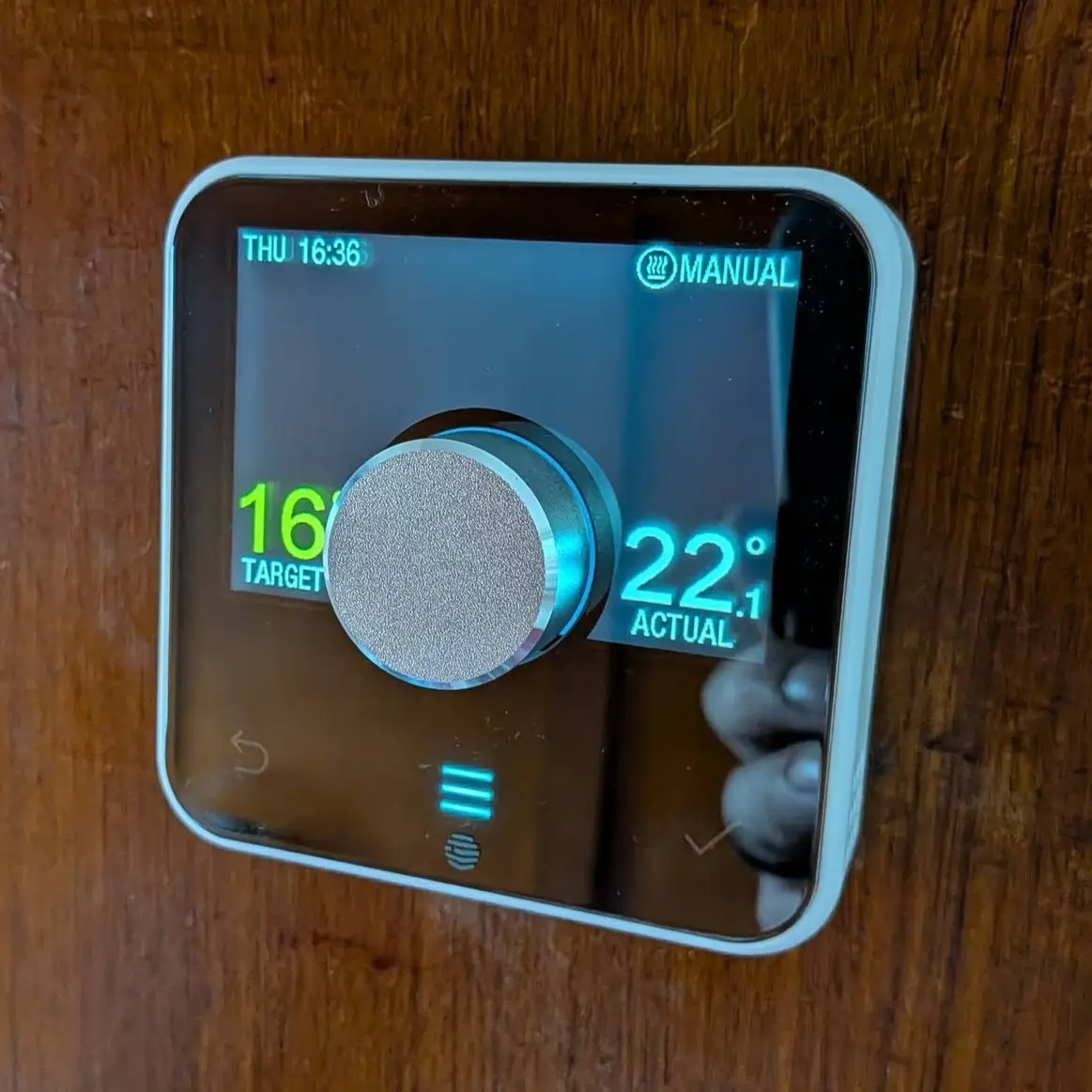 A Hive smart thermostat on a wood-panelled wall, set to 16 degrees target and showing 22.1 degrees actual, in manual mode